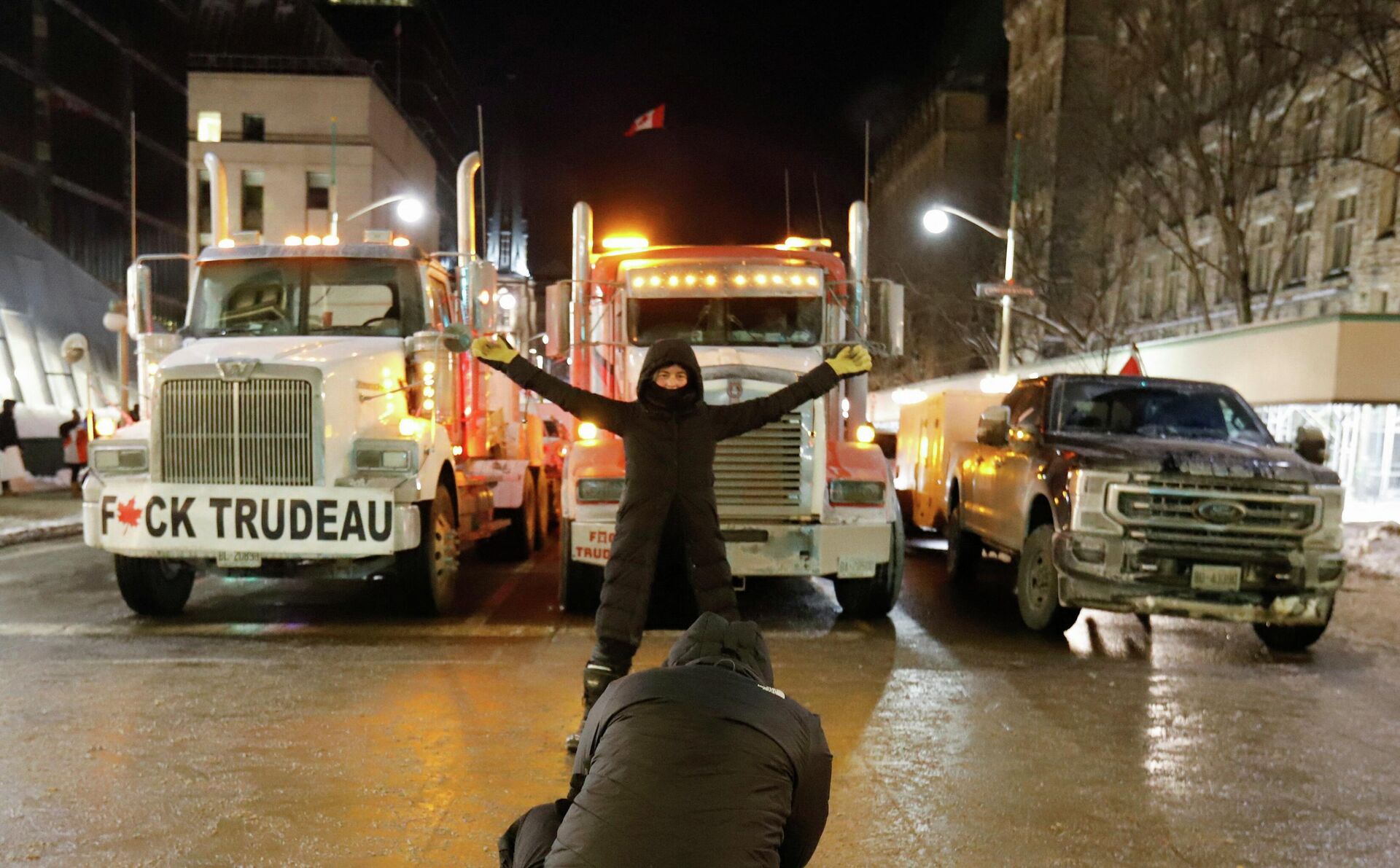 A woman poses for a photo in front of trucks that are part of a trucker convoy to protest coronavirus disease (COVID-19) vaccine mandates for cross-border truck drivers on Parliament Hill in Ottawa, Ontario, Canada, January 28, 2022 - Sputnik International, 1920, 14.02.2022