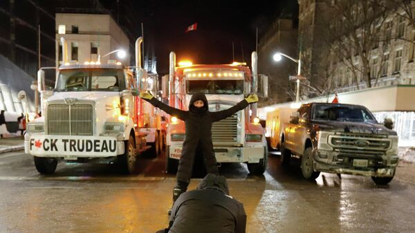 A woman poses for a photo in front of trucks that are part of a trucker convoy to protest coronavirus disease (COVID-19) vaccine mandates for cross-border truck drivers on Parliament Hill in Ottawa, Ontario, Canada, January 28, 2022 - Sputnik International
