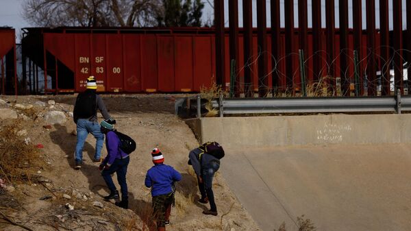Asylum-seeking migrants from Haiti walk near the border wall after crossing the Rio Bravo river to turn themselves in to U.S. Border Patrol agents to request asylum in El Paso, Texas, U.S., as seen from Ciudad Juarez, Mexico January 03, 2022.  - Sputnik International