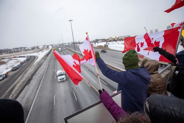 Supporters of truckers gather on a highway overpass in Toronto, Ontario, Canada, to support truck drivers on their way to Ottawa to protest coronavirus (COVID-19) vaccine mandates for cross-border truck drivers on 27 January 2022. - Sputnik International