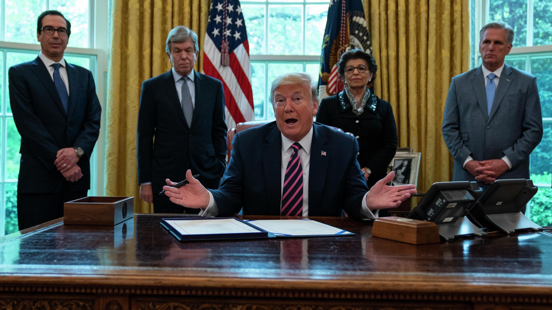 President Donald Trump speaks before signing a coronavirus aid package to direct funds to small businesses, hospitals, and testing, in the Oval Office of the White House, Friday, April 24, 2020, in Washington. From left, Treasury Secretary Steven Mnuchin, Sen. Roy Blunt, R-Mo., Trump, Small Business administrator Jovita Carranza, and House Minority Leader Kevin McCarthy of Calif. (AP Photo/Evan Vucci) - Sputnik International, 1920, 10.02.2022