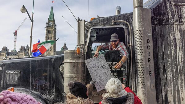 Trucker signs a protestors sign during a rally against COVID-19 on Parliament Hill on January 30, 2022 in Ottawa, Canada.  - Sputnik International