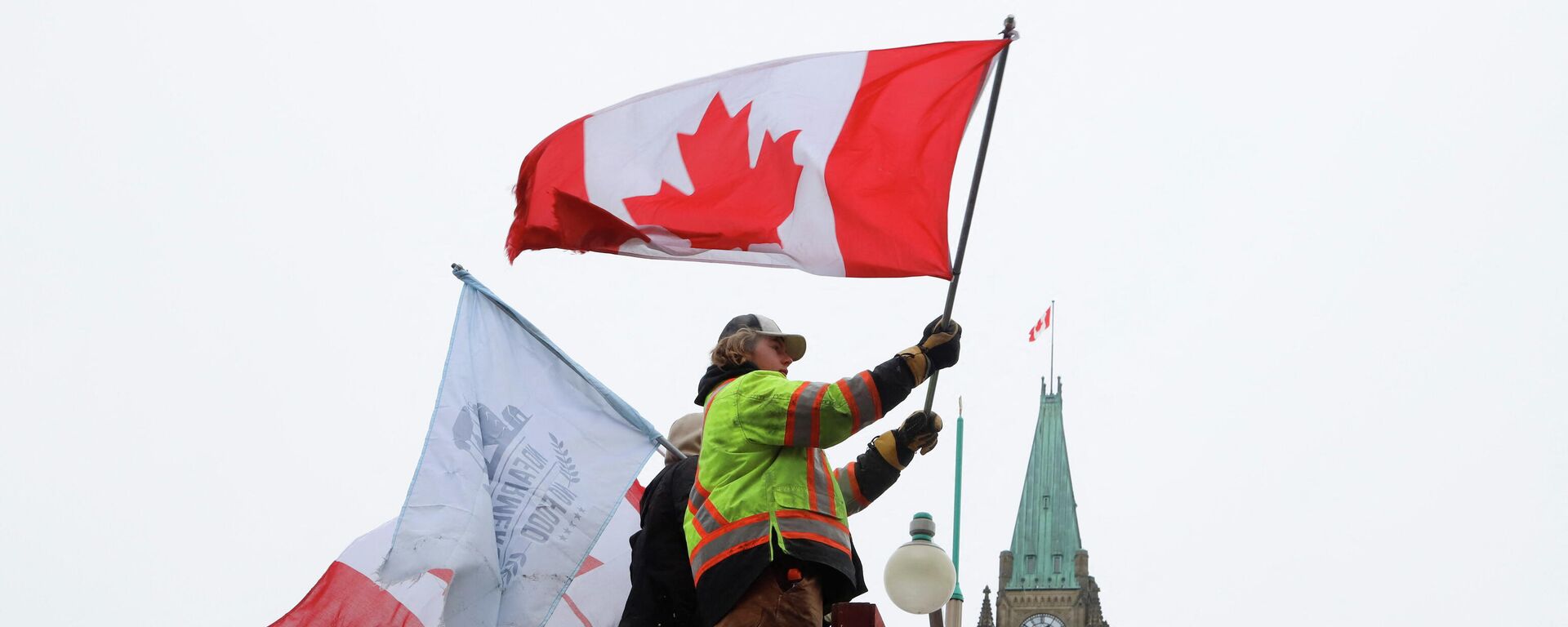 People wave flags on top of a truck in front of Parliament Hill as truckers and their supporters continue to protest against the COVID-19 vaccine mandates in Ottawa - Sputnik International, 1920, 10.02.2022