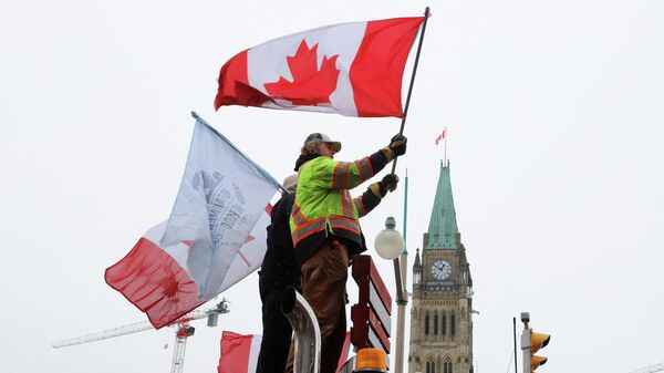People wave flags on top of a truck in front of Parliament Hill as truckers and their supporters continue to protest against the COVID-19 vaccine mandates in Ottawa - Sputnik International