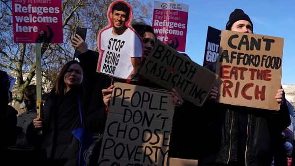 Demonstrators stand with placards in Parliament Square at a protest organised by The People's Assembly to demand action to tackle the cost of living crisis in London on February 12, 2022. - Sputnik International