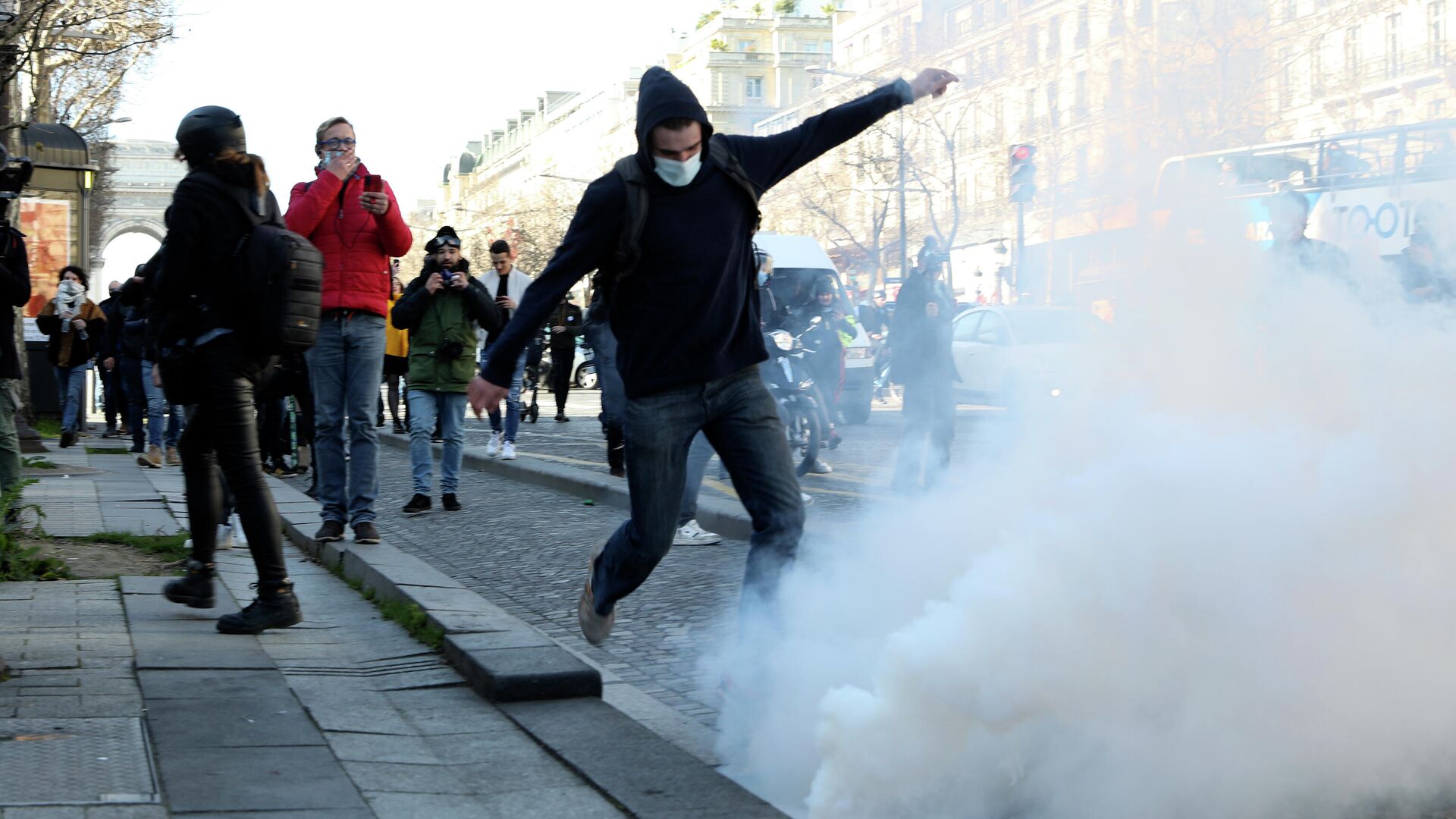 A demonstrator kicks in a tear gas grenade during a protest on the Champs-Elysees avenue, Saturday, Feb.12, 2022 in Paris. Paris police intercepted at least 500 vehicles attempting to enter the French capital in defiance of a police order to take part in protests against virus restrictions inspired by the Canada's horn-honking Freedom Convoy. - Sputnik International, 1920, 13.02.2022