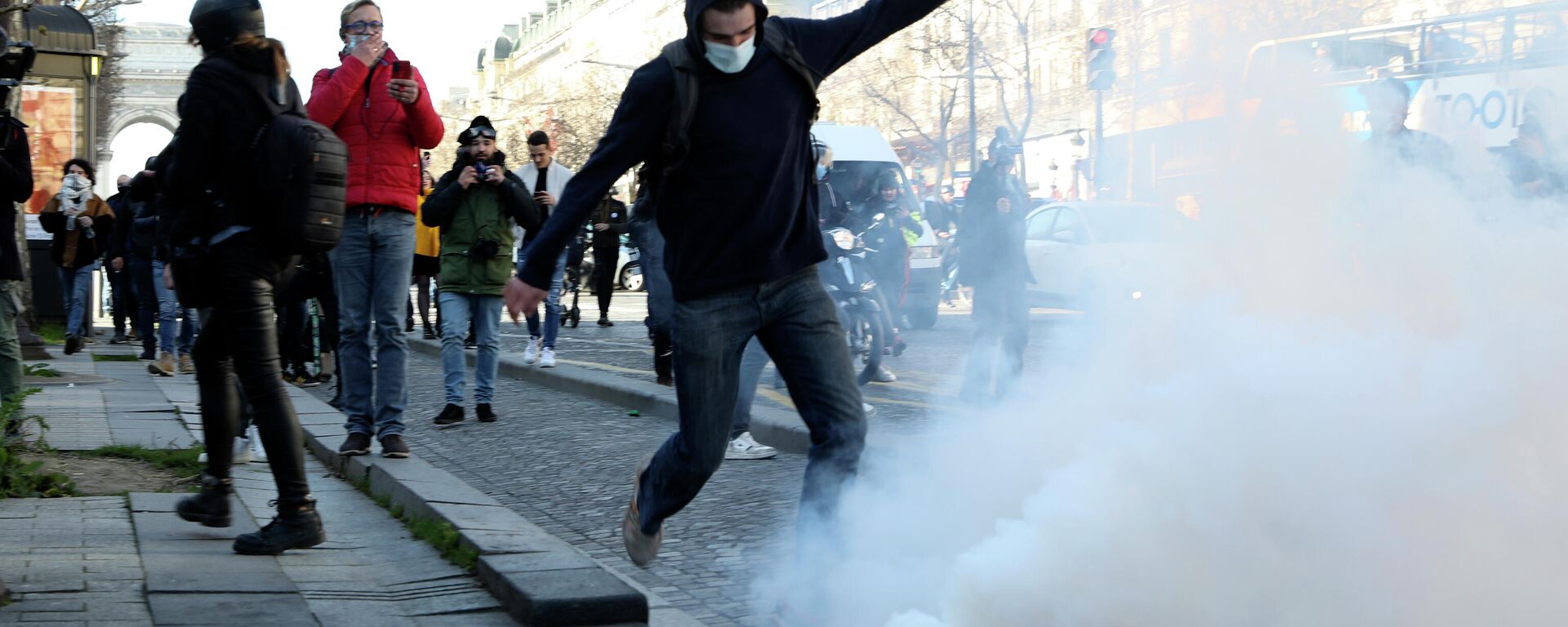 A demonstrator kicks in a tear gas grenade during a protest on the Champs-Elysees avenue, Saturday, Feb.12, 2022 in Paris. Paris police intercepted at least 500 vehicles attempting to enter the French capital in defiance of a police order to take part in protests against virus restrictions inspired by the Canada's horn-honking Freedom Convoy. - Sputnik International, 1920, 13.02.2022