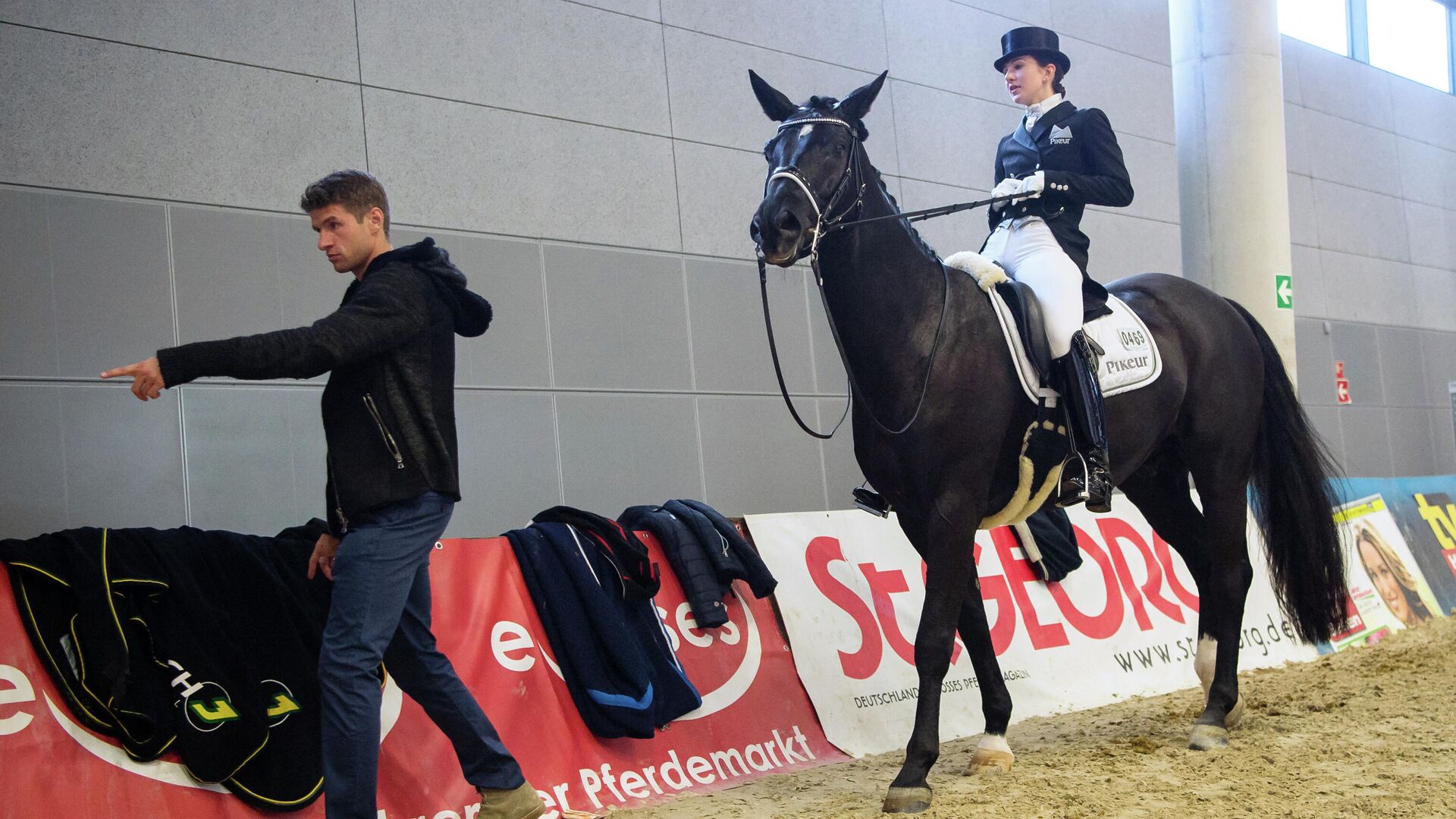 Bayern Munich's midfielder Thomas Mueller (L) gestures next to his wife Lisa Mueller who sits on her twelve year old horse 'Dave' during the Munich Indoors 2015 equestrian tournament on November 8, 2015, in Munich, southern Germany - Sputnik International, 1920, 14.02.2022