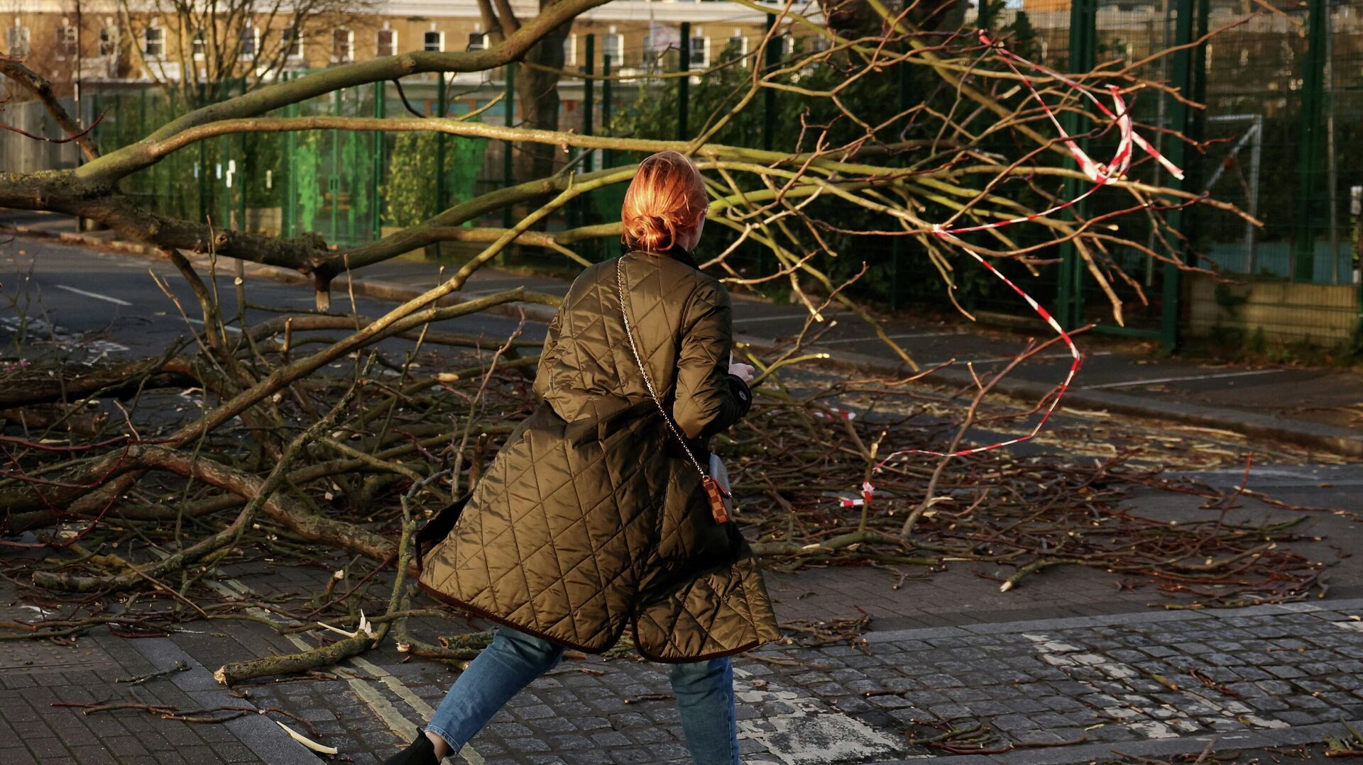 A woman walks past a fallen tree on a side street in Fulham during Storm Eunice, in London - Sputnik International, 1920, 19.02.2022