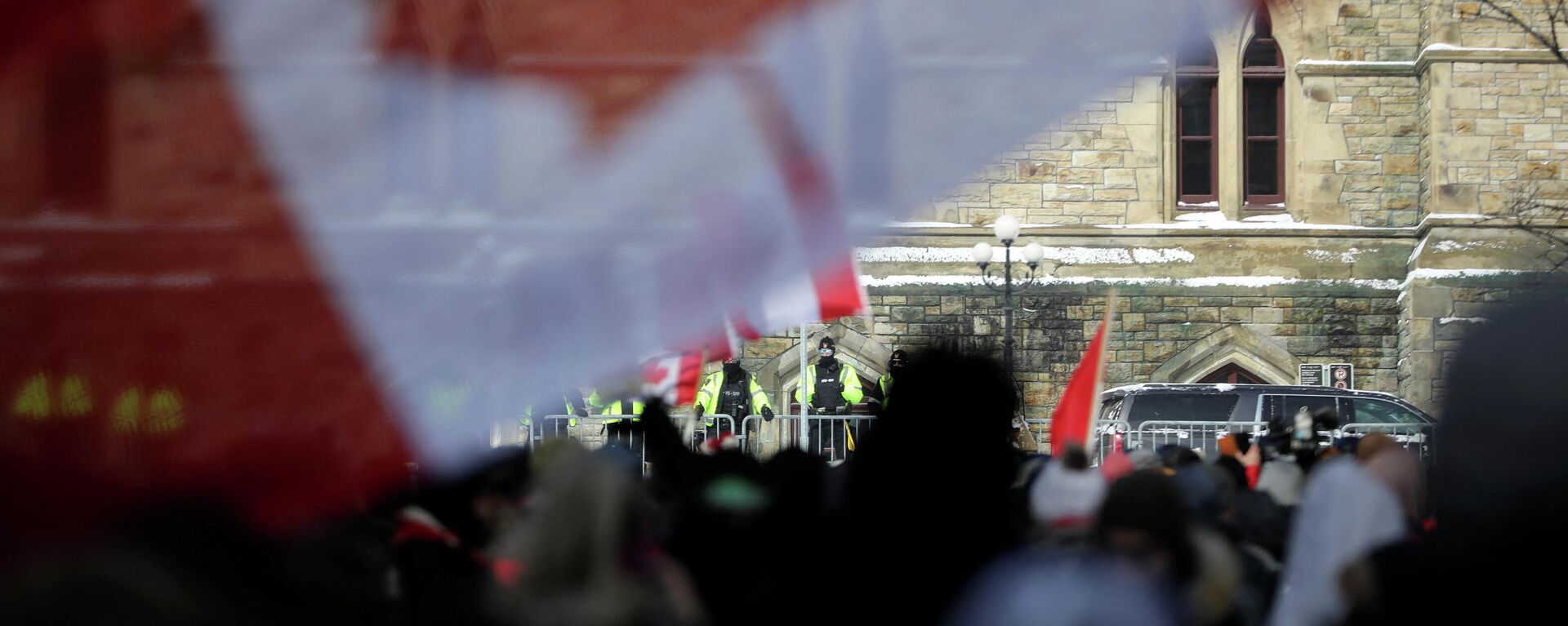 Canadian police officers watch while demonstrators hold Canadian flags, as they work to restore normality to the capital while trucks and demonstrators continue to occupy the downtown core for more than three weeks to protest against pandemic restrictions in Ottawa, Ontario, Canada, February 19, 2022.  REUTERS/Carlos Osorio - Sputnik International, 1920, 19.02.2022