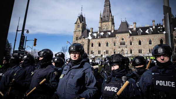 Police block protesters after taking the main street where trucks are parked in Ottawa near Parliament hill  on Saturday, Feb. 19, 2022.  Police resumed pushing back protesters on Saturday after arresting more than 100 and towing away vehicles in Canada’s besieged capital, and scores of trucks left under the pressure, raising authorities’ hopes for an end to the three-week protest against the country’s COVID-19 restrictions.  (AP Photo/Robert Bumsted) - Sputnik International