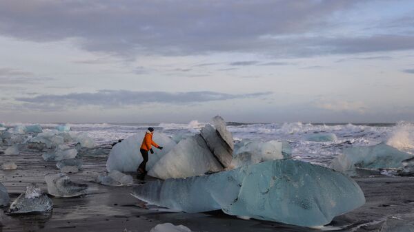 A tourist looks at the blocks of ice that have broken off the Jokulsarlon glacier lagoon at Diamond beach  - Sputnik International