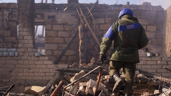 An employee of the Joint Centre for Control and Coordination on ceasefire and stabilization of the demarcation line (JCCC) is seen near a residential building destroyed as a result of shelling by the Ukrainian Armed Forces, in the village of Pionerskoye, Luhansk region, self-proclaimed Luhansk People's Republic, Eastern Ukraine - Sputnik International