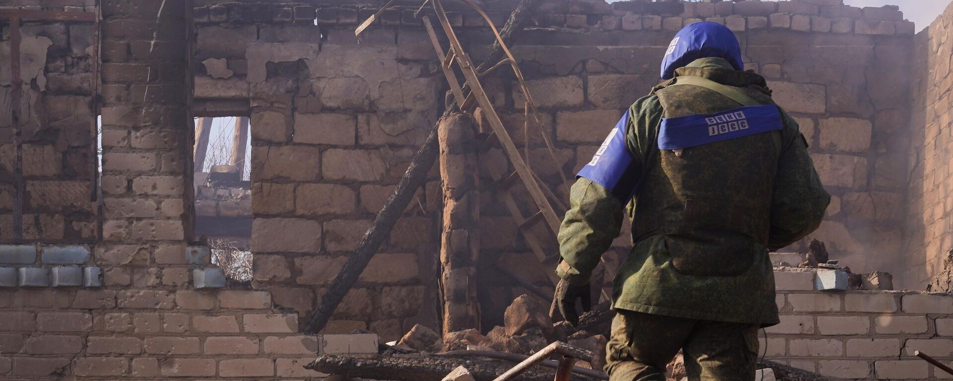 An employee of the Joint Centre for Control and Coordination on ceasefire and stabilization of the demarcation line (JCCC) is seen near a residential building destroyed as a result of shelling by the Ukrainian Armed Forces, in the village of Pionerskoye, Luhansk region, self-proclaimed Luhansk People's Republic, Eastern Ukraine - Sputnik International, 1920, 21.02.2022