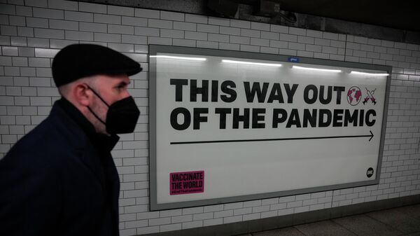 A man wearing a face mask to curb the spread of coronavirus walks past a health campaign poster from the One NGO, in an underpass leading to Westminster underground train station, in London, Thursday, Jan. 27, 2022. - Sputnik International