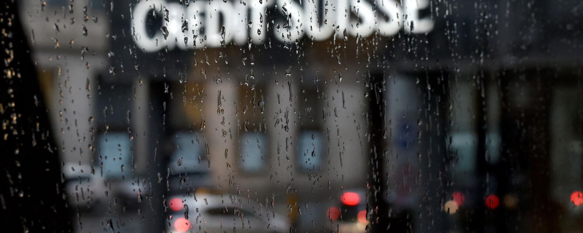 A picture taken on June 13, 2016 shows a branch of Swiss banking giant Credit Suisse behind a window under the rain, in Basel - Sputnik International, 1920, 23.02.2022