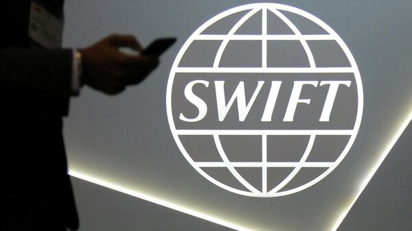 : A man using a mobile phone passes the logo of global secure financial messaging services cooperative SWIFT at the SIBOS banking and financial conference in Toronto, Ontario, Canada October 19, 2017 - Sputnik International