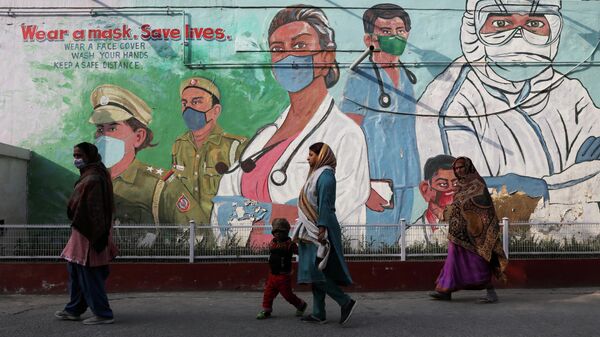 Women walk past a graffiti amidst the spread of the coronavirus disease (COVID-19) in New Delhi, India, February 7, 2022 - Sputnik International