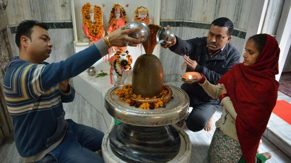 Indian Hindu devotees pour water and milk over a Lingam, representing Lord Shiva, at a temple on the eve of the Maha Shivratri festival in Amritsar on March 3, 2019 - Sputnik International