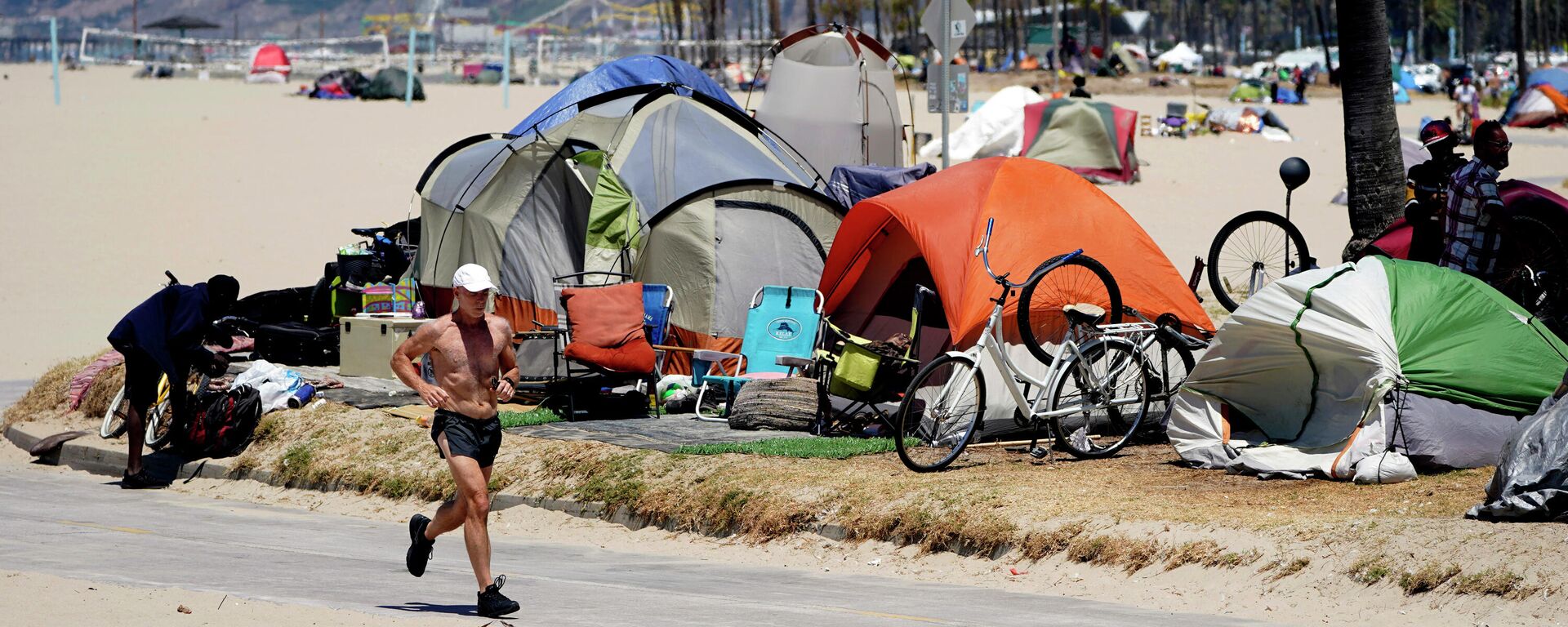  In this June 8, 2021, file photo, a jogger runs past a homeless encampment in the Venice Beach section of Los Angeles. California Gov. Newsom on Thursday, Sept 16, 2021, approved two measures to slice through local zoning ordinances as the most populous state struggles with soaring home prices, an affordable housing shortage and stubborn homelessness. Newson signed the most prominent legislation despite nearly 250 cities objecting that it will, by design, undermine local planning and control. - Sputnik International, 1920, 08.03.2024