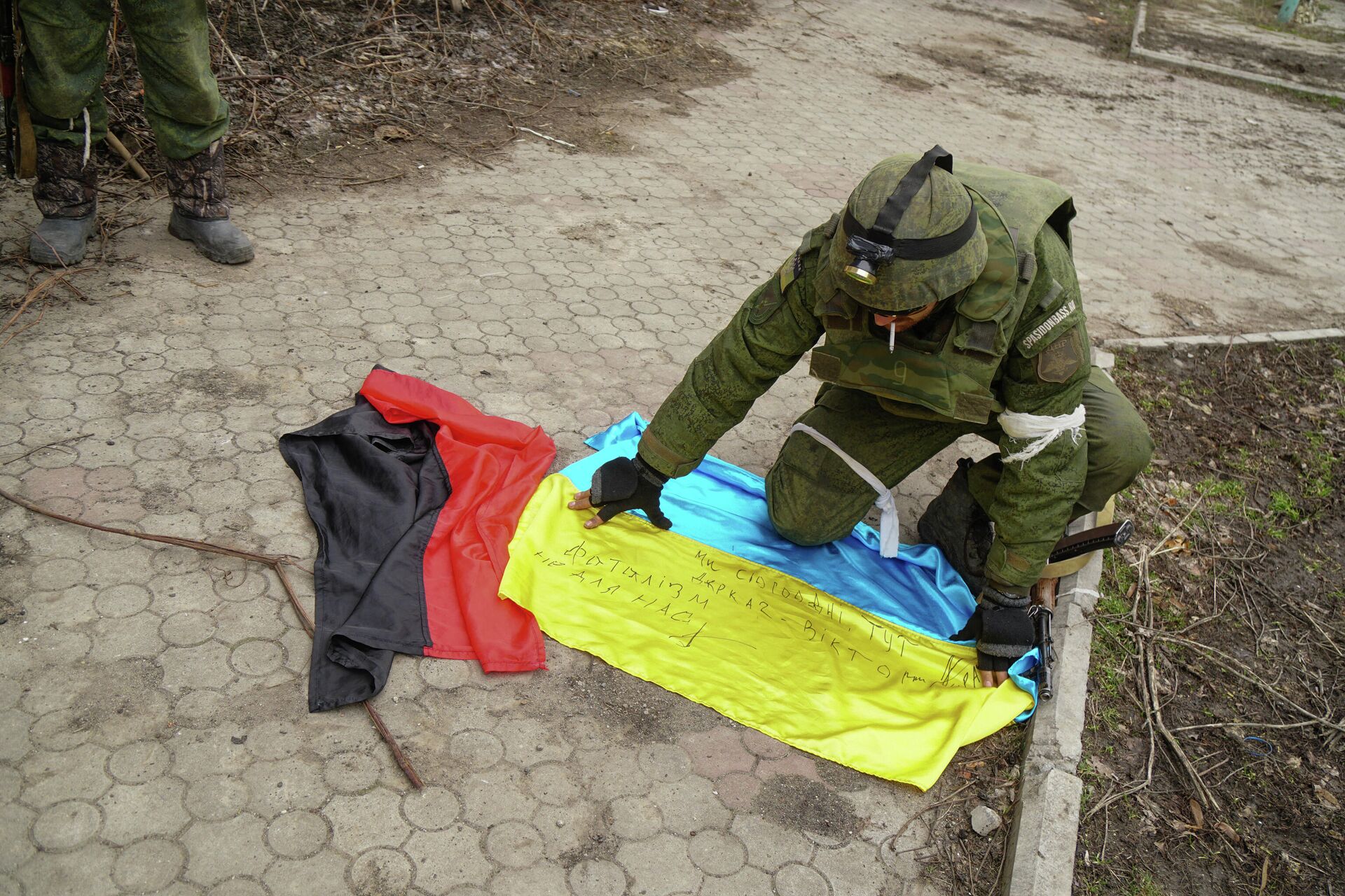 A serviceman of militia of Donetsk People's Republic (DPR) demonstrates flags of Ukraine and of Right Sector right-wing   radical group (banned in Russia) found in a camp of Ukrainian forces outside Mariupol, Ukraine - Sputnik International, 1920, 05.03.2022