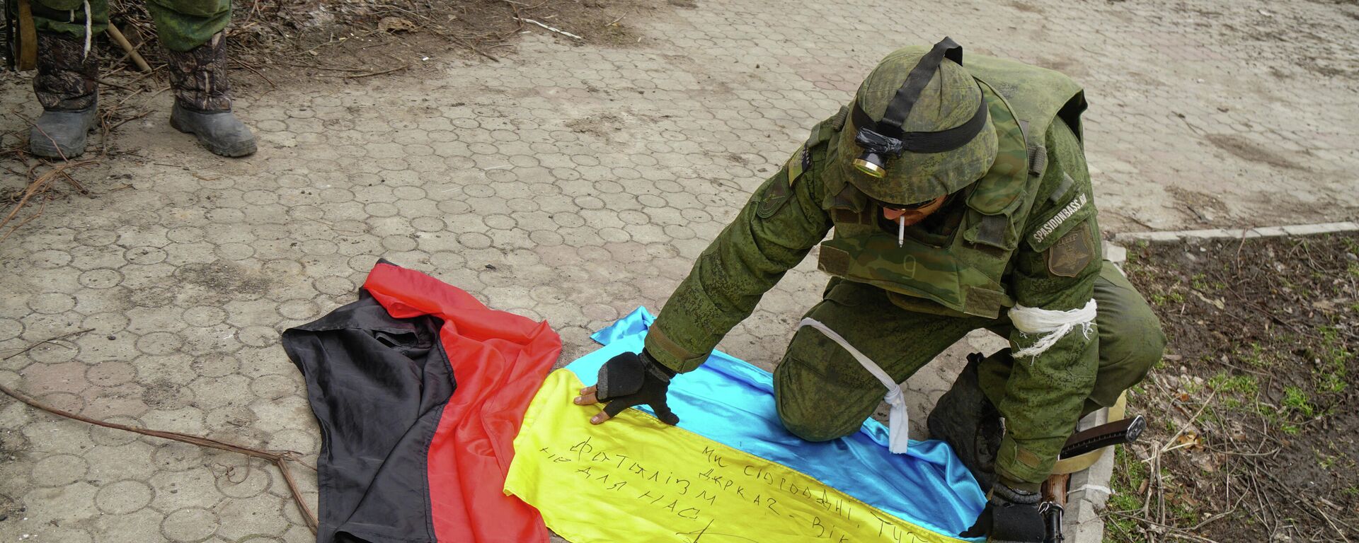 A serviceman of militia of Donetsk People's Republic (DPR) demonstrates flags of Ukraine and of Right Sector right-wing   radical group (banned in Russia) found in a camp of Ukrainian forces outside Mariupol, Ukraine - Sputnik International, 1920, 04.03.2022