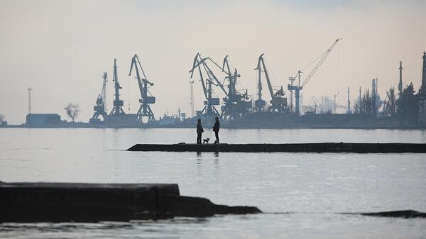 A couple walks a dog on a pier at a coast of the Sea of Azov in Ukraine's industrial port city of Mariupol on February 23, 2022 - Sputnik International