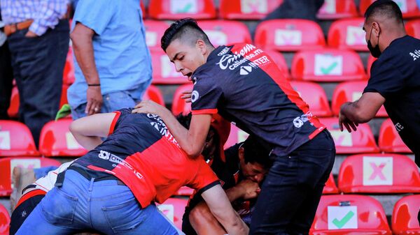 People are beaten at the seating area of the Corregidora stadium, leaving at least 22 injured in a brawl when soccer fans stormed the field during a top-flight match between mid-table Queretaro and last year's Liga MX champions Atlas, in Queretaro, Mexico, March 5, 2022. - Sputnik International
