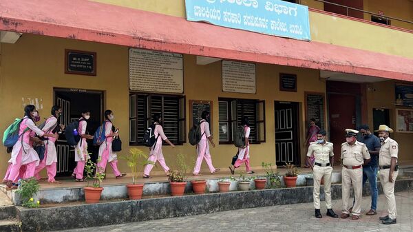 Schoolgirls arrive to attend their classes as police officers stand inside the premises of a government girls school after the recent hijab ban, in Udupi town in the southern state of Karnataka, India, February 14, 2022. - Sputnik International