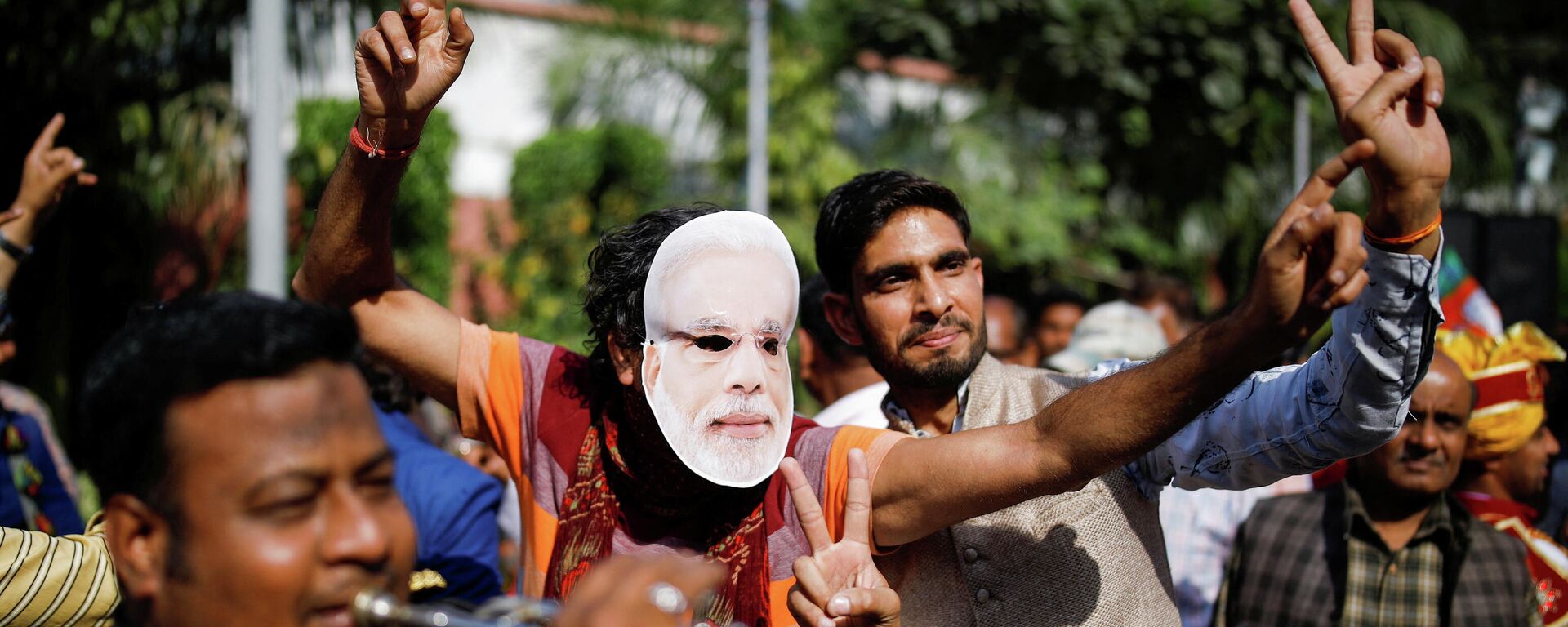 A supporter of India's ruling party Bharatiya Janata Party (BJP) wearing a mask of Prime Minister Narendra Modi dances as he celebrates after learning the initial poll results at the party headquarter in New Delhi - Sputnik International, 1920, 11.03.2022