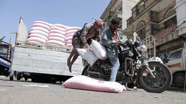 A worker jumps as he loads sacks of wheat flour on a motorcycle outside a wholesale food shop in Sanaa, Yemen February 28, 2022 - Sputnik International