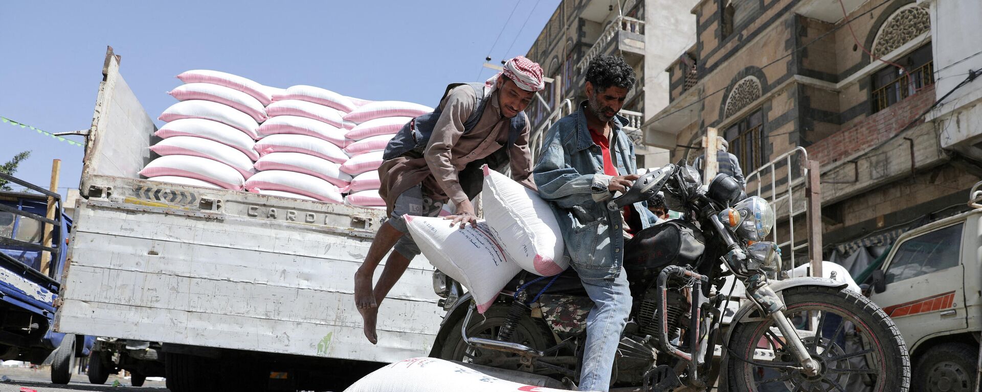 A worker jumps as he loads sacks of wheat flour on a motorcycle outside a wholesale food shop in Sanaa, Yemen February 28, 2022 - Sputnik International, 1920, 12.03.2022