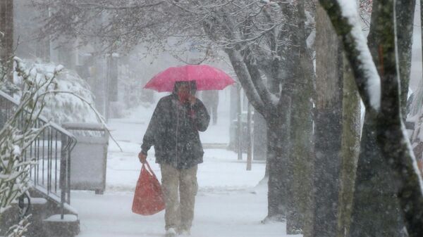 A man walks through Lancaster City, Pa., with his shopping bag during a snowstorm Saturday, March 12, 2022.  - Sputnik International
