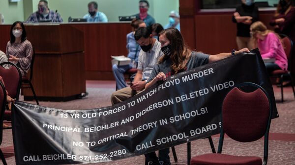 A woman holds up her sign against Critical Race Theory (CRT) being taught during a Loudoun County Public Schools (LCPS) board meeting in Ashburn, Virginia on October 12, 2021 - Sputnik International