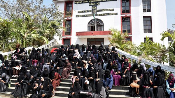 Students and supporters sit in front of the office of the deputy commissioner as a sign of protest in Shivamogga district in India’s Karnataka state on February 17, 2022, a day after educational institutions reopened in southern India under tight security after authorities banned public gatherings following protests over Muslim girls wearing the hijab in classrooms.  - Sputnik International