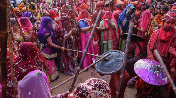 Women hit revellers with sticks as a traditional practice during the Lathmar Holi celebrations, the Hindu spring festival of colours, at Nandgaon village in India’s Uttar Pradesh state on March 12, 2022 - Sputnik International