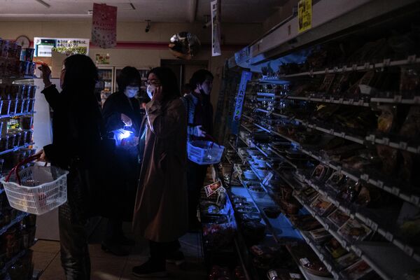 People shop in a store in a residential area during a power outage in Koto district in Tokyo on March 16, 2022, after a powerful 7.3-magnitude quake jolted east Japan. - A powerful 7.3-magnitude quake jolted eastern Japan on the night of March 16,, 2022 - Sputnik International
