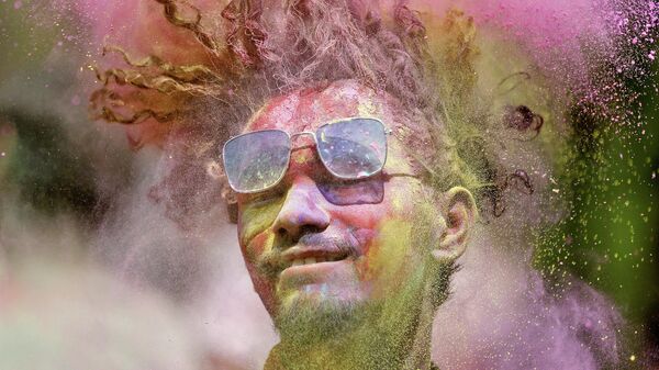 A man covered in coloured powder shakes his head during Holi celebrations in Ahmedabad, India, March 17, 2022 - Sputnik International