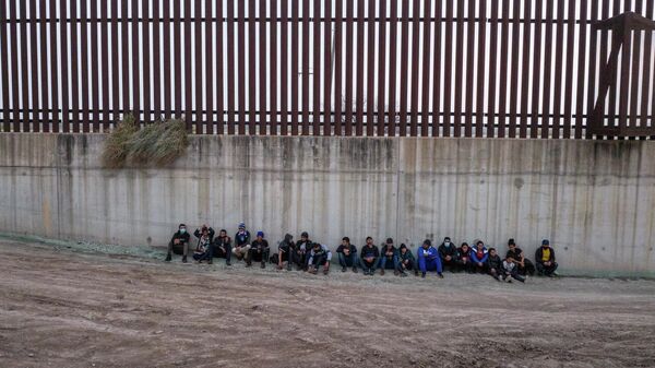 Asylum seeking migrants from Central America line up near the border wall as they await to be processed by agents after crossing the Rio Grande river into the United States from Mexico in Penitas, Texas, U.S., February 23, 2022. Picture taken with a drone. - Sputnik International