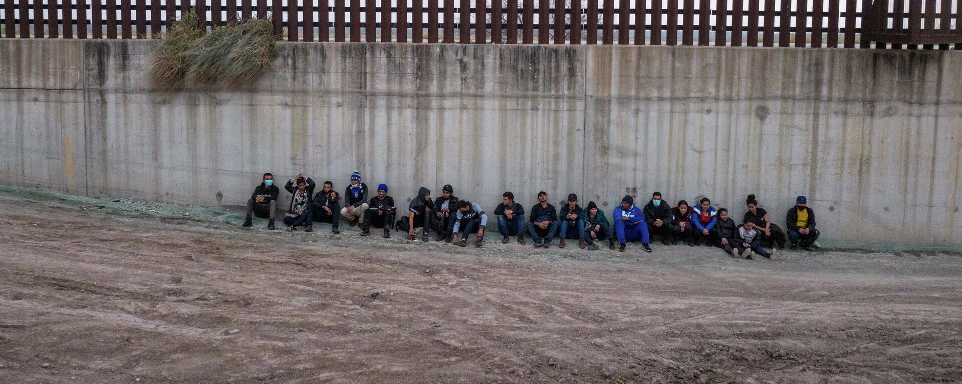 Asylum seeking migrants from Central America line up near the border wall as they await to be processed by agents after crossing the Rio Grande river into the United States from Mexico in Penitas, Texas, U.S., February 23, 2022. Picture taken with a drone. - Sputnik International, 1920, 18.03.2022