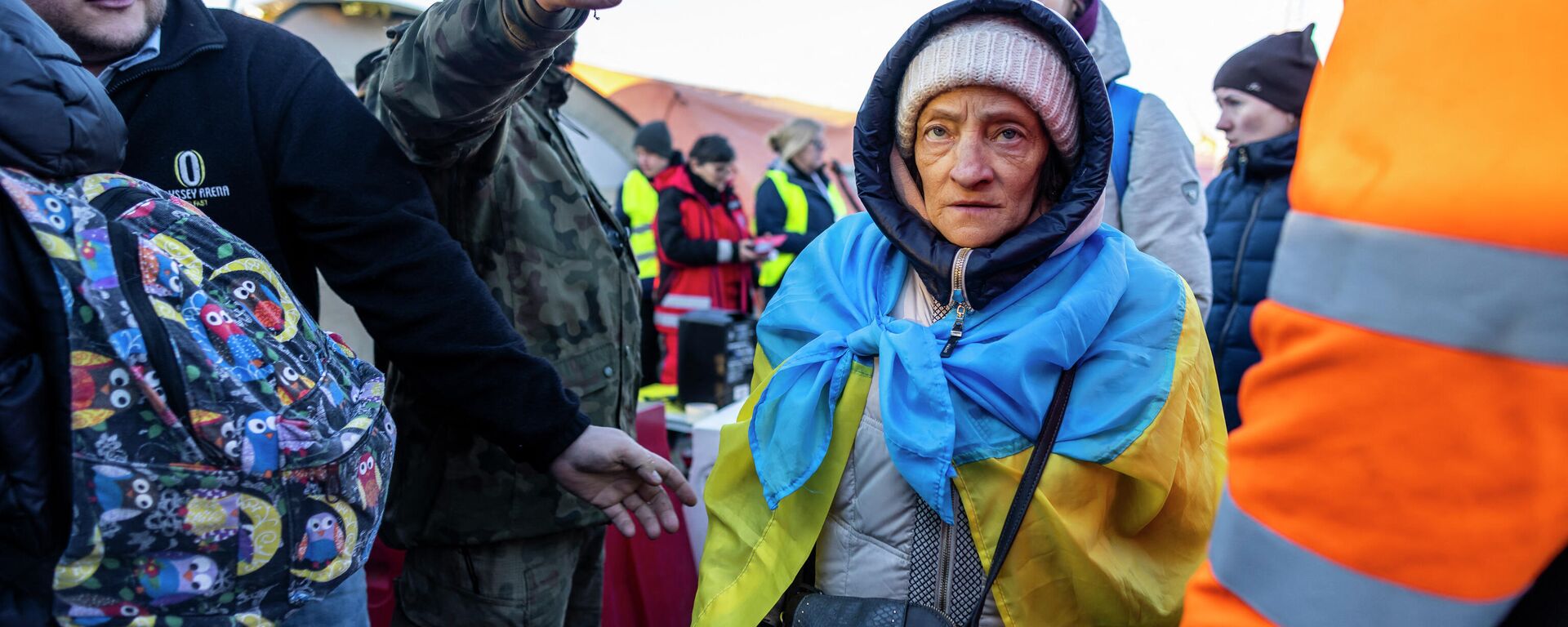 People, including an elderly woman wearing a Unkraine flag, line up to get into the buses for further transportation at the Medyka Polish-Ukrainian border crossing on March 18, 2022 - Sputnik International, 1920, 19.03.2022