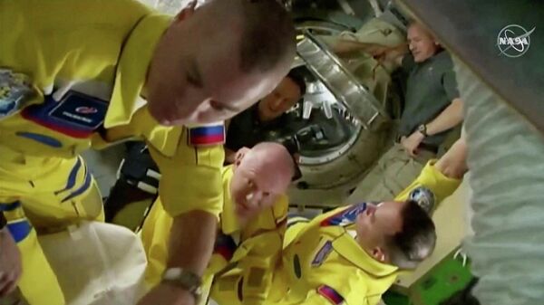 Russian cosmonauts Oleg Artemyev, Denis Matveev and Sergey Korsakov arrive wearing yellow and blue flight suits at the International Space Station after docking their Soyuz capsule March 18, 2022 i a still image from video. Video taken March 18, 2022. - Sputnik International