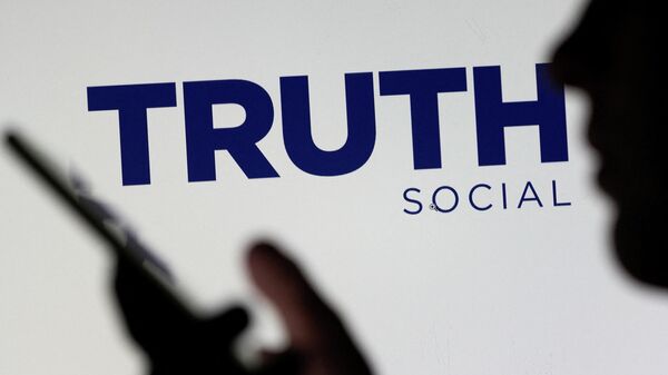The Truth social network logo is seen displayed behind a woman holding a smartphone in this picture illustration taken February 21, 2022. - Sputnik International