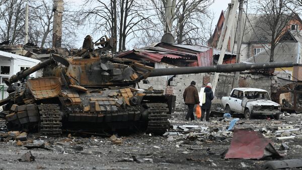Local residents pass by the destroyed tank of the Ukrainian armed forces in the city of Volnovakha that came under control of the Donetsk People's Republic, in Donetsk People's Republic. - Sputnik International