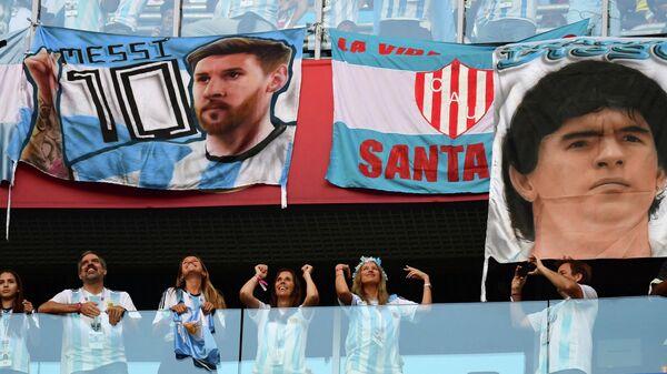 Argentina fans stand under a posters, the first bearing the picture of Argentina's forward Lionel Messi and the second bearing the portrait of retired Argentina forward Diego Maradona, ahead of the Russia 2018 World Cup Group D football match between Nigeria and Argentina at the Saint Petersburg Stadium in Saint Petersburg on June 26, 2018. - Sputnik International