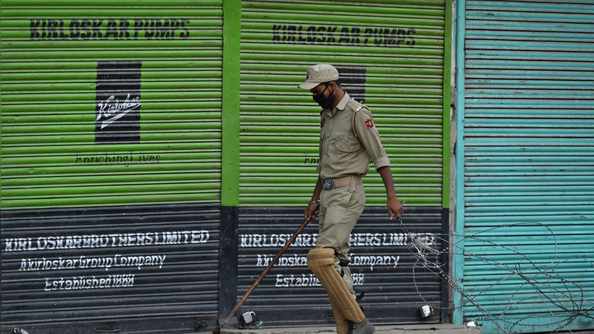 An Indian police personnel pulls barbed wire next to shuttered stores during heavy restrictions on movements in Srinagar on September 10, 2019, on the 10th day of the holy Islamic month of Muharram - Sputnik International, 1920, 25.03.2022