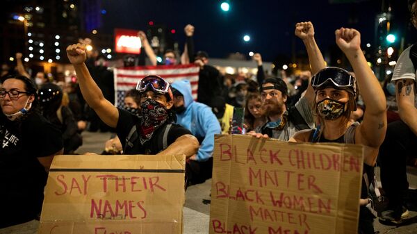 Demonstrators wearing protective face masks raise their fists as they sit in silence for nine minutes in a peaceful protest against the death in Minneapolis police custody of George Floyd, at 19th and Broadway in Denver, Colorado, U.S., June 1, 2020 - Sputnik International