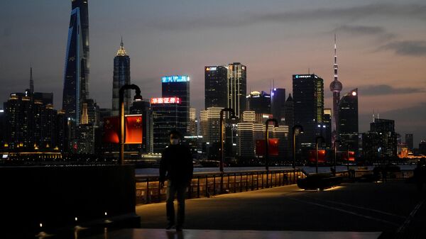A man walks in front of Lujiazui financial district, seen across the Huangpu river at dusk, amid the lockdown in Pudong area to contain the spread of the coronavirus disease (COVID-19) in Shanghai, China March 28, 2022 - Sputnik International
