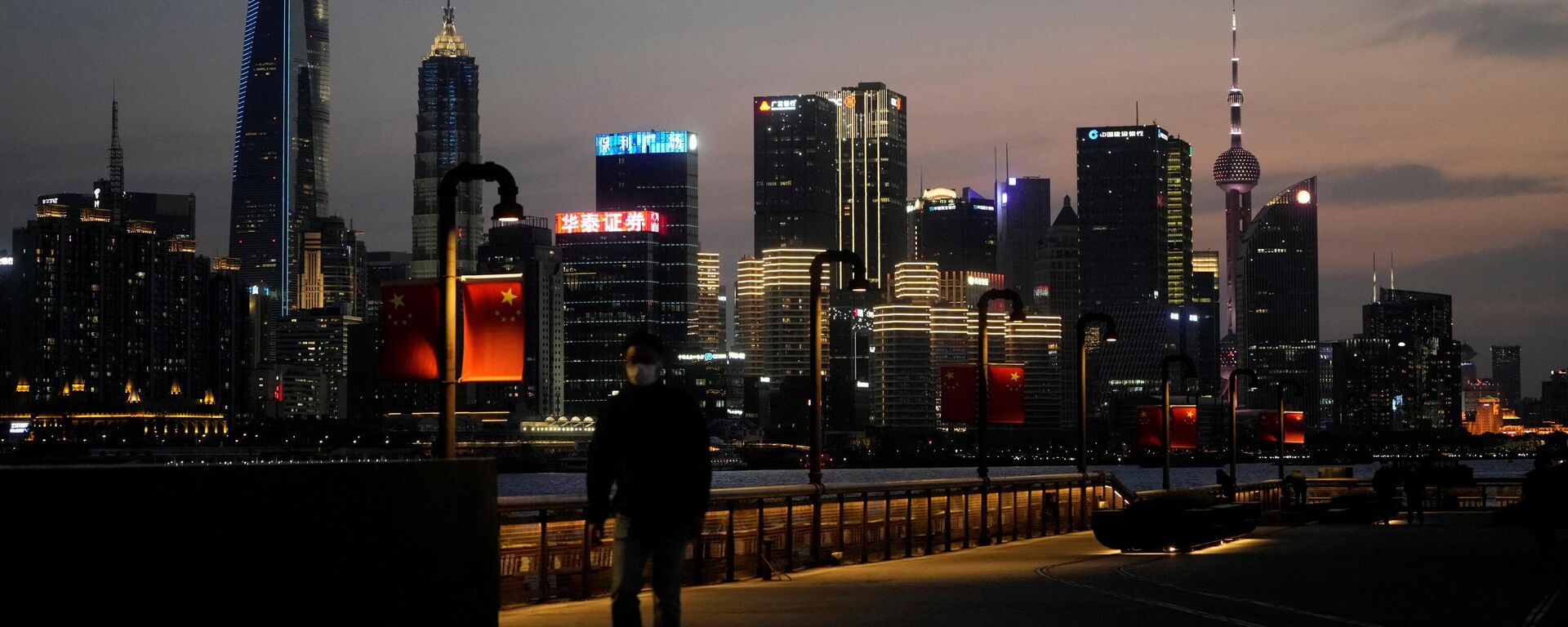 A man walks in front of Lujiazui financial district, seen across the Huangpu river at dusk, amid the lockdown in Pudong area to contain the spread of the coronavirus disease (COVID-19) in Shanghai, China March 28, 2022 - Sputnik International, 1920, 04.04.2022
