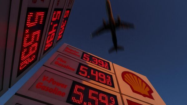 An aircraft flies over a sign displaying current gas prices as it approaches to land in San Diego, California, U.S., February 28, 2022 - Sputnik International